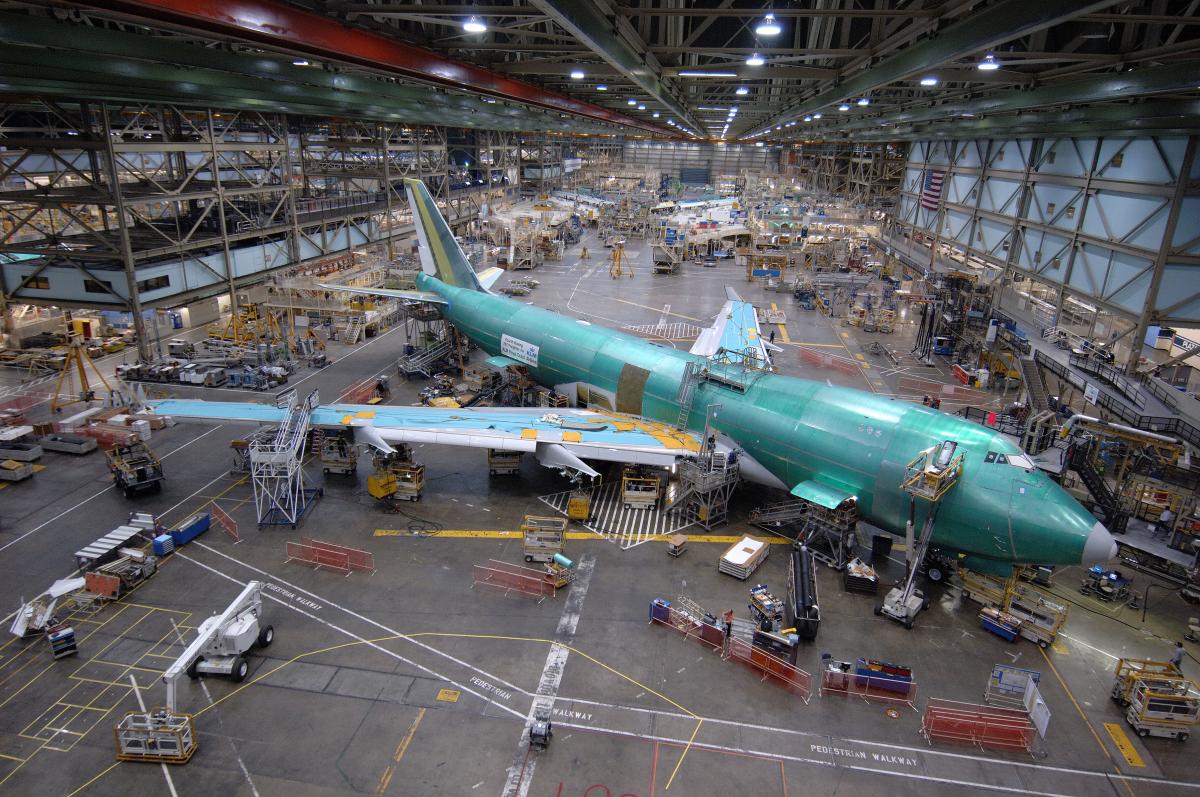 Top view of aircraft in a closed dock with lot of activity around.