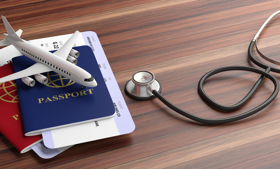 Stethoscope placed on a table beside a travel passport and a miniature of a flight.