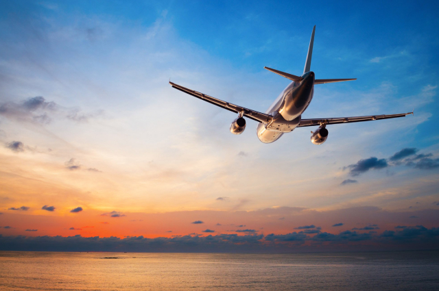 An Image of an aircraft flying towards the clouds on a sunset..