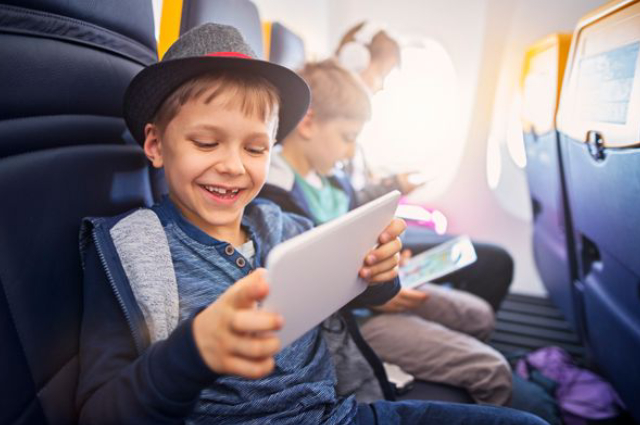 An image of kids playing in the tablet during their flight travel.