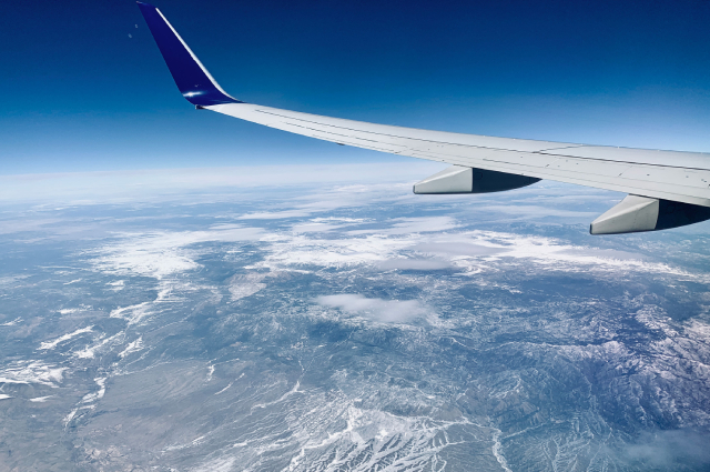 Image of An aircraft wings above the clouds and earth.